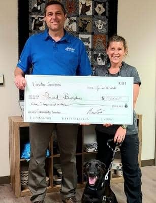man presenting giant check to woman and dog